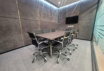 Professional meeting room featuring a dark wood table, black leather chairs, and gray acoustic wall panels.