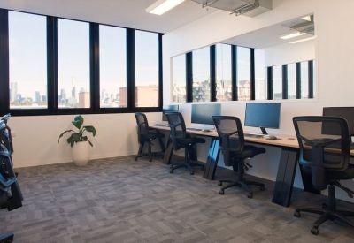 Bright open-plan workspace with a row of desks and large windows overlooking the city skyline.