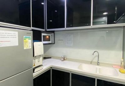 Modern communal kitchen with sleek black cabinetry and white countertops.