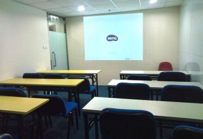 Classroom-style training room with rows of tables and a projector screen.