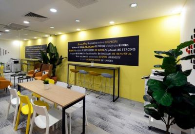 Bright communal break area with a yellow feature wall and long wooden dining table.
