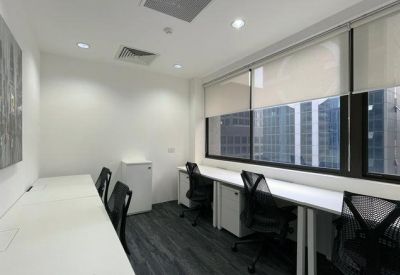 Window-side workspace with long white desks and ergonomic black chairs.