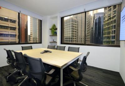 Spacious boardroom with a light wood table and large windows overlooking the city.