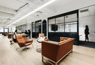 Open-plan coworking area with various seating options including leather chairs and a long bench table.