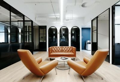 Bright breakout space featuring tan leather armchairs, a sofa, and modern arched wall alcoves.