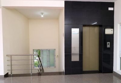 Clean building lobby featuring a sleek black elevator bank and a stainless steel staircase railing.