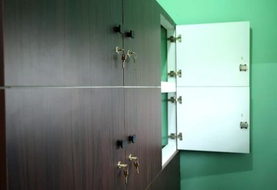 Dark wood storage lockers with secure key locks located against a green feature wall.