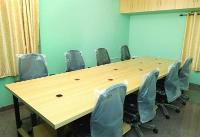 Spacious six-person conference table with blue mesh office chairs in a brightly lit room.
