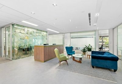 Modern reception lobby with a wood-panelled desk, velvet sofa, and decorative glass partition.