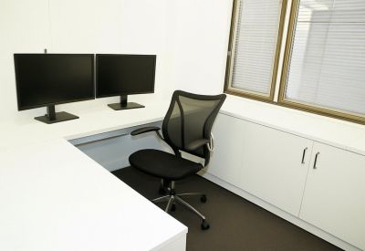 Private corner office with an L-shaped desk and dual monitor setup.