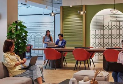 Cozy informal meeting space featuring red chairs and a large wooden table against a green feature wall.
