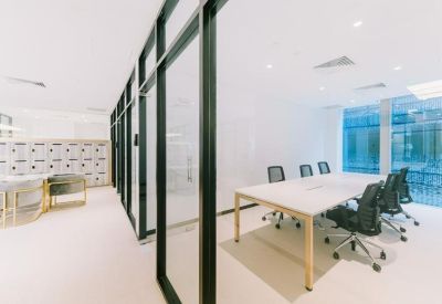 Professional boardroom with a long white table and black ergonomic mesh chairs.
