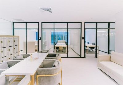 Bright breakout space with a long white table, soft sofa, and glass partitions.