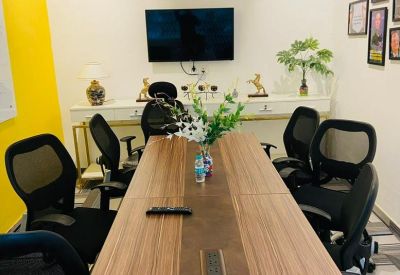 Modern meeting room with a large wooden table and black mesh chairs.