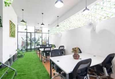 Spacious communal area with desks and green decor.