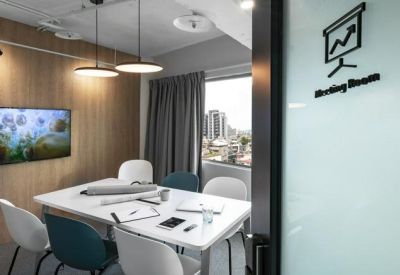 Private meeting room with a wooden feature wall, wall-mounted screen, and white table.