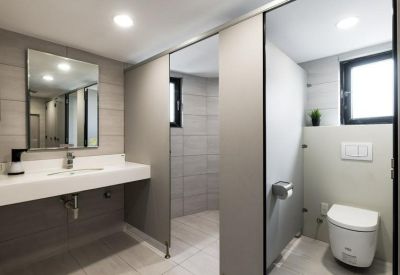 Modern bathroom with a white floating sink and private toilet stall.