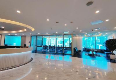Spacious reception area with a curved white desk and bright, polished marble floors.