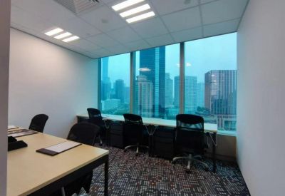 Shared office suite with workstations facing large windows and a city skyline view.