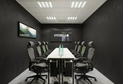 Professional meeting room with a long white table, gray ergonomic chairs, and dark gray walls.