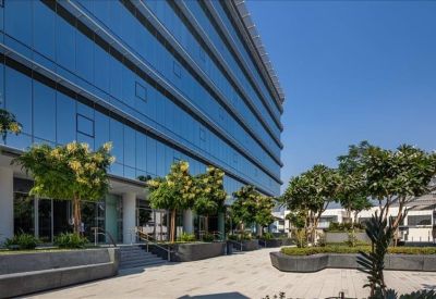 Modern glass building facade with manicured landscaping and outdoor seating areas.