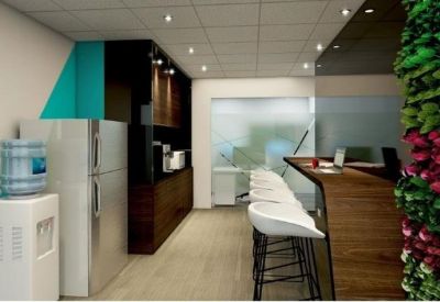 Office breakout area featuring a wooden bar counter, white stools, and a vibrant vertical garden wall.