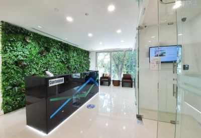 Modern reception area with a black branded desk and a lush green plant wall feature.