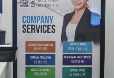 Branded signage board detailing company services next to a potted plant.