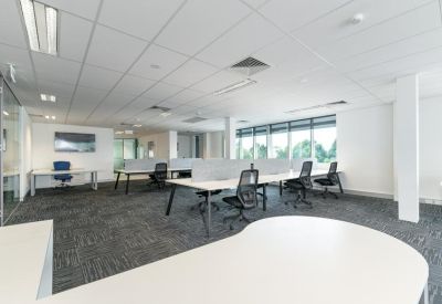 Expansive open-plan office floor showing multiple desk clusters and bright overhead lighting.