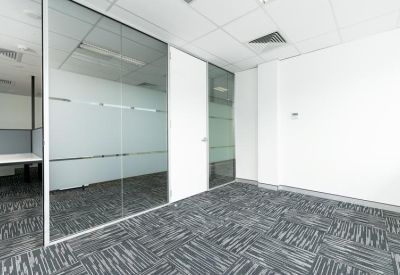 Bright private office suite with floor-to-ceiling glass partitioning and grey patterned carpet.