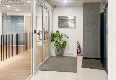 Entrance to Global Tech Park on O’ Shaughnessy Road featuring glass doors, a potted plant, and a directory plaque.