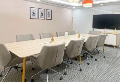 Modern conference room with a long wooden table and grey upholstered chairs.