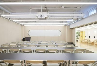 Spacious, bright training room with rows of long tables and a wall-mounted whiteboard.
