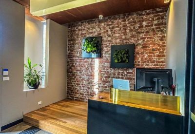 Reception desk with wood panelled floors, a brick feature wall, and hanging greenery.