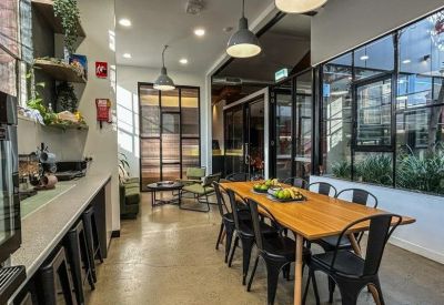 Spacious communal dining area with a large timber table and modern black seating.
