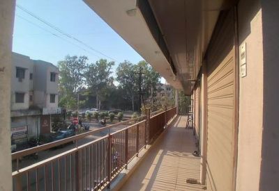 Outdoor balcony walkway with a metal railing overlooking the street and trees.