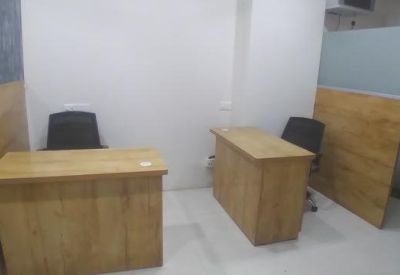 Bright workspace featuring two wooden desks and black ergonomic chairs.