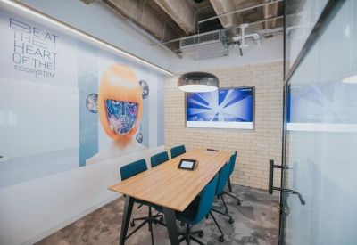 Modern meeting room with wood-topped table, teal chairs, and vibrant wall graphics.
