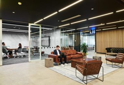 Bright lounge area with leather armchairs and glass-fronted breakout spaces.
