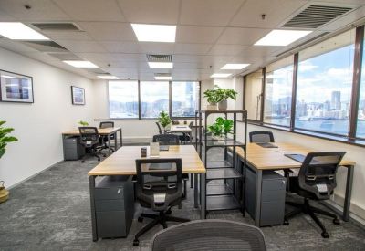 Open-plan workspace with multiple wooden desks and expansive city and harbor views.
