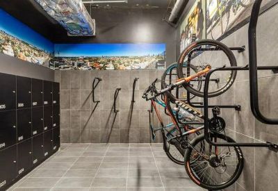 Secure bike storage room with wall-mounted racks, lockers, and colorful city skyline murals.