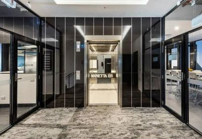 Internal corridor featuring glass partitions and a central elevator with dark marble surrounds.