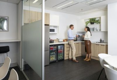 Modern kitchen and breakout area with wooden cabinetry and people socializing.