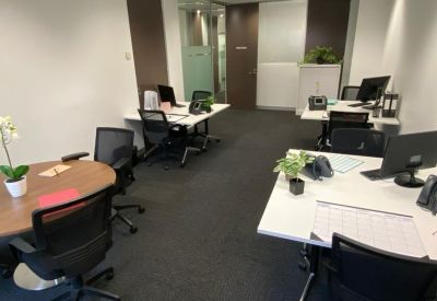 Open plan workspace featuring several white desks and ergonomic black chairs.