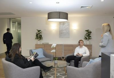 Professional board room with a large white table, comfortable chairs, and wall art.