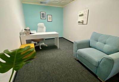 Private office suite with a white desk, blue accent wall, and a comfortable armchair.