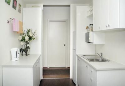 Clean white communal kitchen area with a sink, microwave, and kettle.