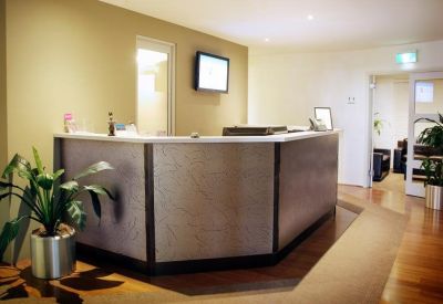 Modern reception desk with wooden flooring and a large indoor plant.