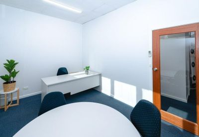Modern meeting room with a round white table, blue chairs, and a timber-framed door.