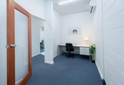 Bright office with a large desk, ergonomic chair, and indoor greenery.